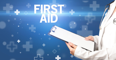 doctor writes notes on the clipboard with FIRST AID inscription, first aid concept