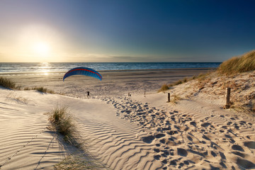 man paragliding on beach at sunset by sea
