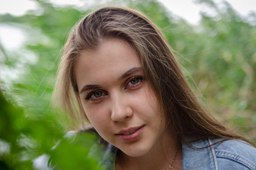 
Portrait of a young beautiful girl on a background of green trees in the garden