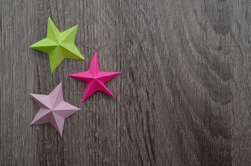 Fototapeta na wymiar three bright origami stars folded from colorful paper
