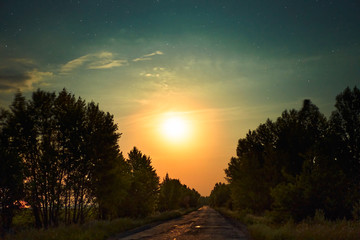 Night road with orange moon shining galaxy stars space dust in the universe, Long exposure...