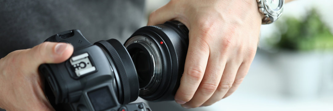 Male hands putting on modern digital camera professional lens