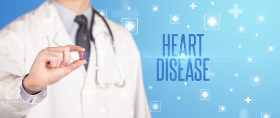 Close-up of a doctor giving a pill with HEART DISEASE inscription, medical concept