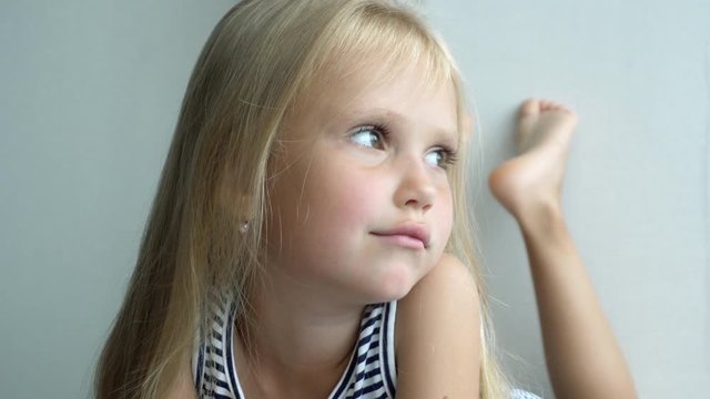 The blonde girl dreams, smiles. Portrait of a blonde girl 5 years old