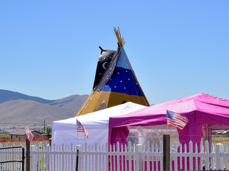 Portable canopies in front of a tall teepee.