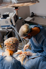 Blepharoplasty plastic surgery operation for modifying the eye region of the face in medical clinic. 2 doctors do plastic cosmetic operation for woman. Surgeon makes an incision with a surgical knife