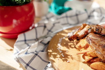 food photography grilled meat French fries in the cafe a bright Sunny natural light and shadow from the leaves of plants