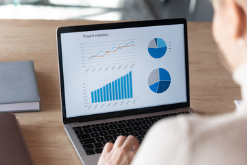Focus on computer screen with increasing graphs and colorful charts of project financial statistics. Focused young businesswoman analyzing marketing strategy sales profitability, economics concept. - obrazy, fototapety, plakaty