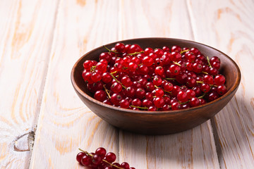 Fresh sweet red currant berries in wooden bowl, wood table background, angle view
