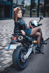 Urban motosport passion. Nice looking girl and her modern powerful sport bike. Motosport hobby portrait.