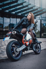 Naklejka na ściany i meble Urban motosport passion. Nice looking girl and her modern powerful sport bike. Motosport hobby portrait.