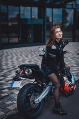 Naklejka na ściany i meble A nice looking woman at the streets with her urban sport motorcycle. Motorbike sport hobby. Modern custom bike.