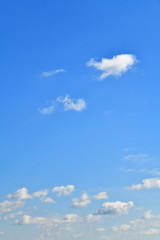 Blue skies on a clear day. White cumulus clouds float across the sky.