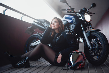 Fototapeta na wymiar The bridge road in sunlight. Pretty beauty girl with her own dark casual motorbike on the bridge. Motosport passion portrait.