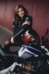Fototapeta na wymiar Sunny photo of female biker and motorcycle. Urban motosport hobby. Motosport passion.