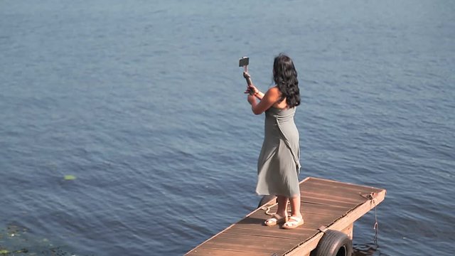 A woman blogger with a mobile phone is blogging by the river
