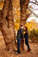 man and a woman standing near tree in autumn Park.