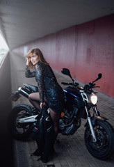 Naklejka na ściany i meble Sunny photo on bridge with girl and casual motorcycle. Modern female motosport hobby. Dark powerful motorbike.