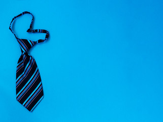 Blue heart-shaped striped tie on a blue background. Copy space