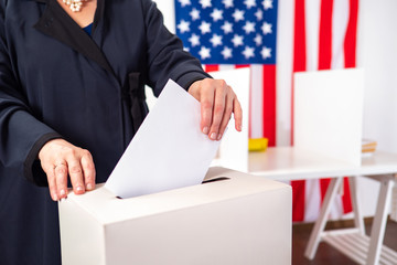 USA. US elections. Woman tosses election bill into a box. Human voter on background of USA national...