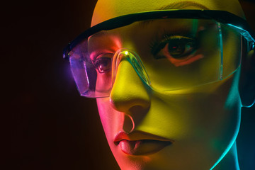 Humanoid robot. Manikin face with glasses. Woman robot face close up. Robotics. Concept - artificial intelligence. Close-up of an artificial intelligence robot head. Creation of robotics. Neon light