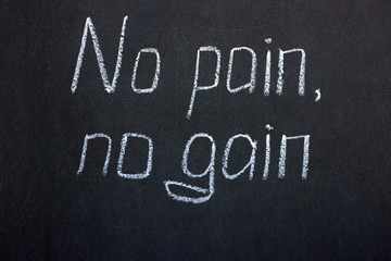 The inscription "no pain, no gain". Chalk lettering on a dark board