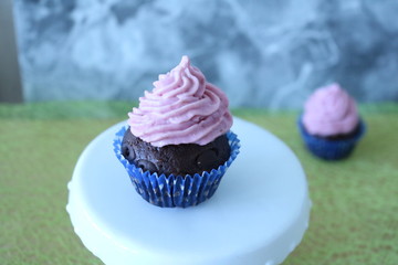Schokoladencup cake mit Himbeertoppinghäubchen auf weißer Etagere