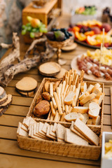 Fototapeta na wymiar Wicker bread and cereal tray with sliced loaf, bread sticks and cookies on a wooden holiday table.