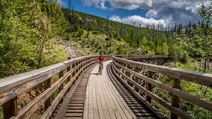 Fototapeta premium Biking over the Wooden Trestle Bridges of the abandoned Kettle Valley Railway in Myra Canyon near Kelowna, British Columbia, Canada