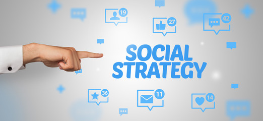 Close-Up of cropped hand pointing at SOCIAL STRATEGY inscription, social networking concept