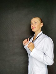 smiling female doctor in white coat holding stethoscope.