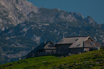 Fototapeta na wymiar Typical old wooden cottages on the top of the hill on Velika planina, a mountain plateau in central Slovenia on a warm summer day.