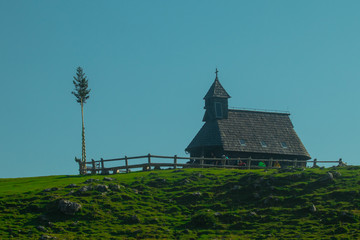 Typical old wooden chapel on the top of the hill on Velika planina, a mountain plateau in central Slovenia on a warm summer day.
