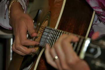 Hands play on an acoustic guitar