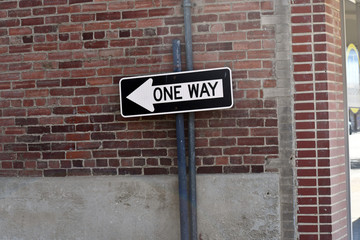 Fototapeta na wymiar One-way sign on a brick building