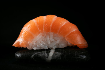 One sushi salmon on a rock in the dark