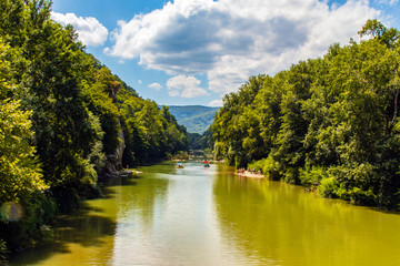  Russia city resort. People sail in a rowboat along the river against the mountain rock Cockerel on a sunny summer day. Water attractions and outdoor activities at the resort