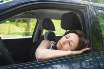 Very tired woman sleeping on a car window.driving safety concept.sleeping at the wheel