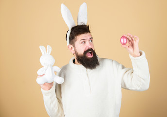 Naklejka premium Funny bunny man soft ears. Easter activities concept. Weirdo concept. Celebrate Easter. Guy bearded hipster weird bunny with long white ears beige background. Easter rabbit. Man wearing rabbit suit