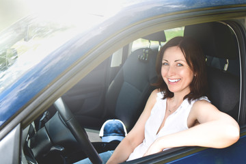 Happy adult woman driving a car and smiling. success happy brunette woman is driving a car. Portrait of happy female driver.