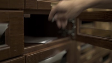 Hand getting out a letter from wooden mailbox. Opening a mailbox receiving an envelope letter, closes a mailbox with a key, handheld close up shot