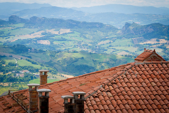Old Ceramic Tile, roof. View of the surroundings of the Republic of San Marino. Chimneys and stormwater, lightning rods. mountains and fields in the background. Italy