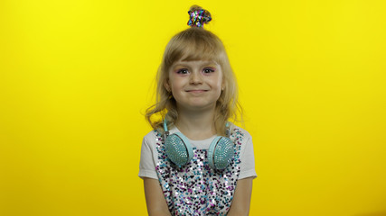 Joyful child smiling, feeling carefree joyful after hearing funny, silly joke on yellow background