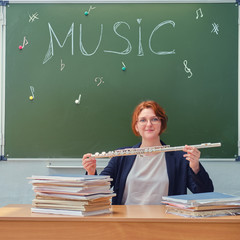 Happy music teacher smiling while sitting at her desk with books