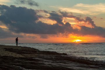 Fototapeta premium A lone man watching the sunset on the east shore of Oahu, Hawaii