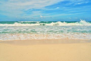 Fototapeta na wymiar tropical sea waves on the beach with white clouds
