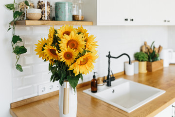 sunflowers bouquet in vase on the kitchen. View on white simple modern kitchen in scandinavian style