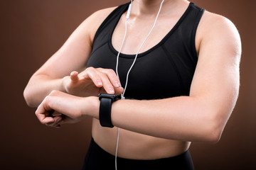 Obraz na płótnie Canvas Mid section of young sportswoman in activewear switching on her fitbit on wrist