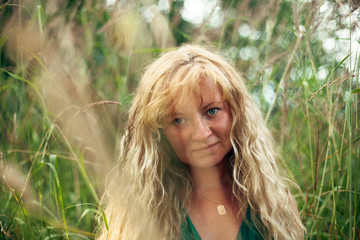 Portrait of a woman with light brown hair in green meadow.