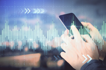 Double exposure of man's hands holding and using a digital device and forex graph drawing. Financial market concept.